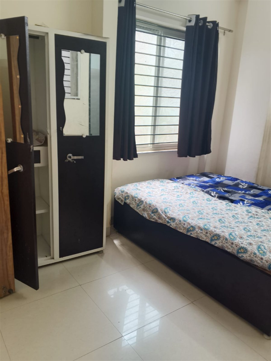 Trishakti Girls Residency room with steel wardrobe, mirror and bedding